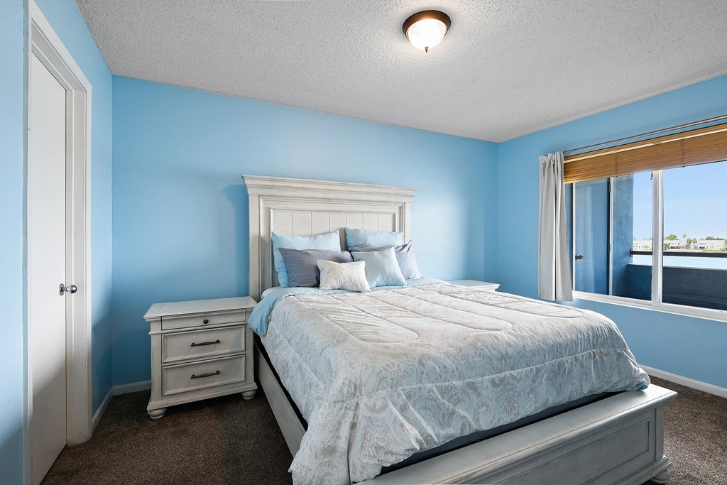 A bedroom with a bed, nightstand, and window.