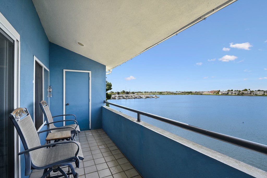 A balcony with two chairs and a table overlooking a body of water.