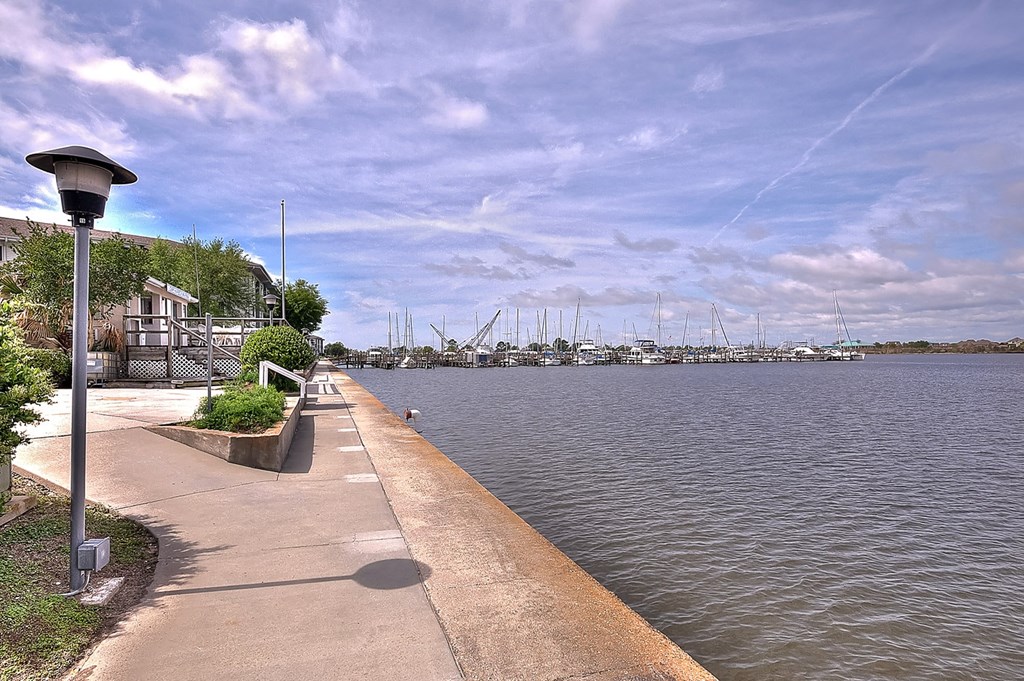 A walkway next to a body of water with boats in the distance.