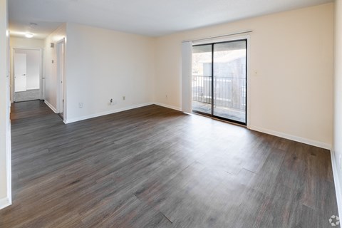 A room with wooden flooring and a sliding glass door leading to a balcony.