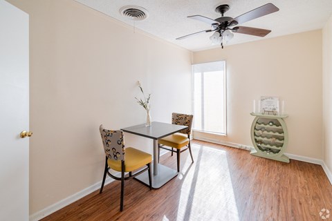 A room with a table and chairs and a fan.