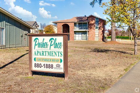 A sign for Parker Place Apartments is in front of a building.