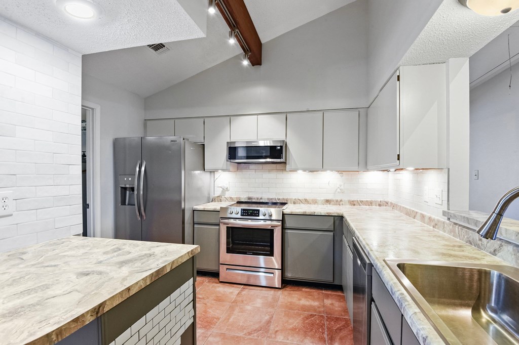 A kitchen with a refrigerator, oven, and microwave.
