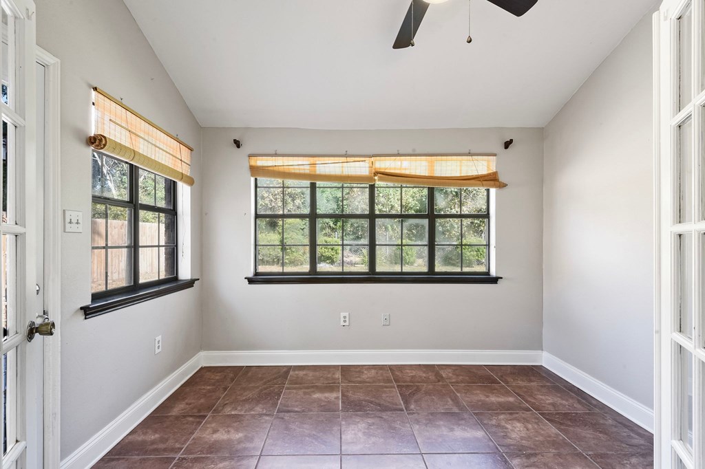 A room with a brown tile floor and a ceiling fan.
