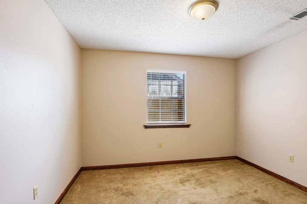 A room with a window and carpeted floor.