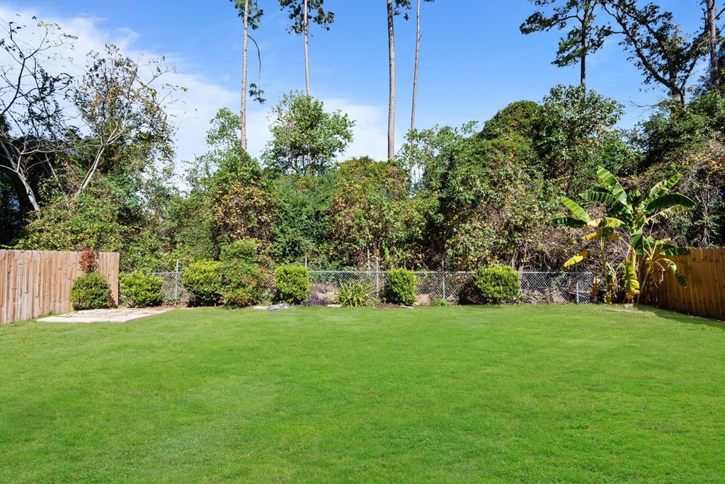 A backyard with a green lawn and trees.