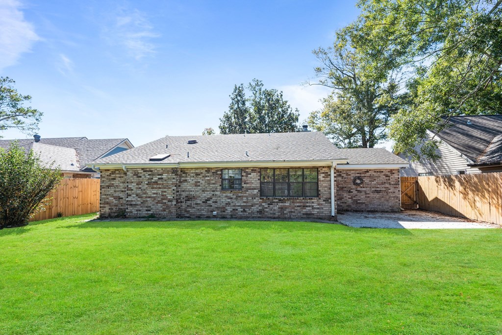 A house with a stone wall and a green lawn.