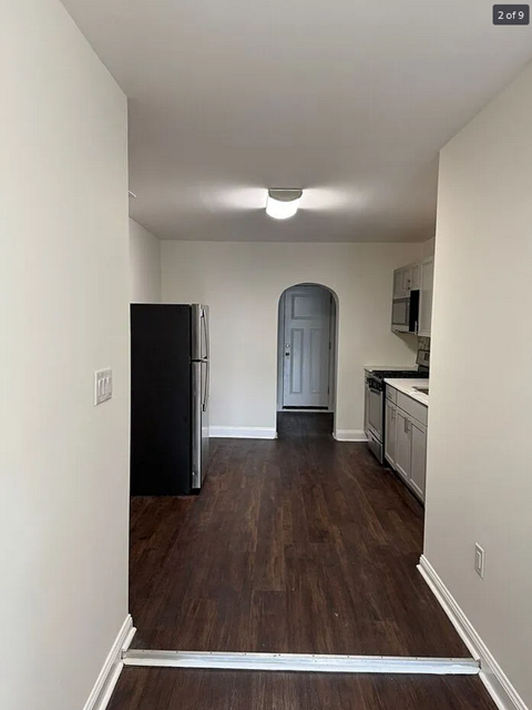 an empty kitchen with a refrigerator and a door
