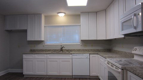 A kitchen with white cabinets and a granite countertop.