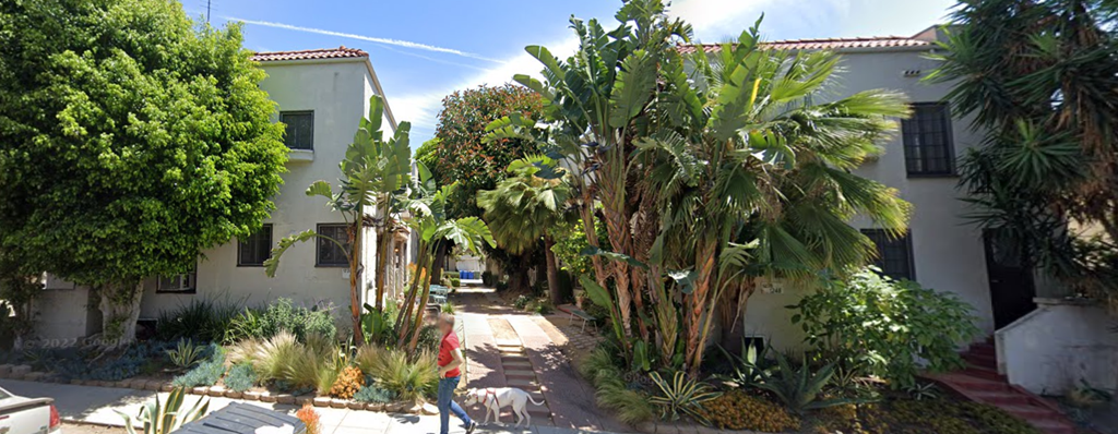 A person walking a dog on a sidewalk.