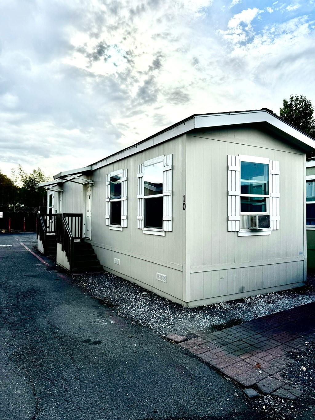 a small white house with white windows and a driveway