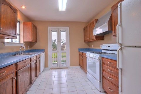 A kitchen with white appliances and wooden cabinets.
