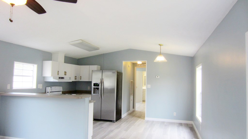 A kitchen with a refrigerator, stove, and ceiling fan.