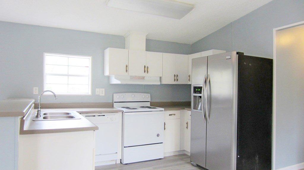 A kitchen with white appliances and cabinets.
