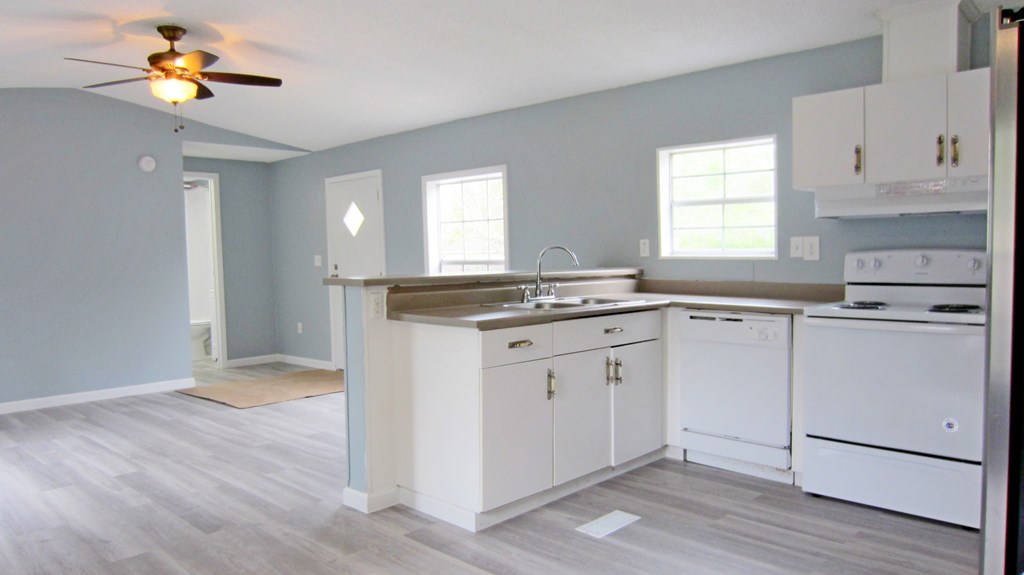 A kitchen with white cabinets and a wooden floor.