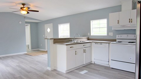 A kitchen with white cabinets and a wooden floor.