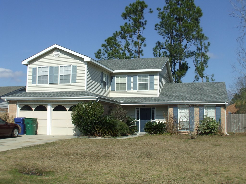 A house with a grey roof and a green trash can.