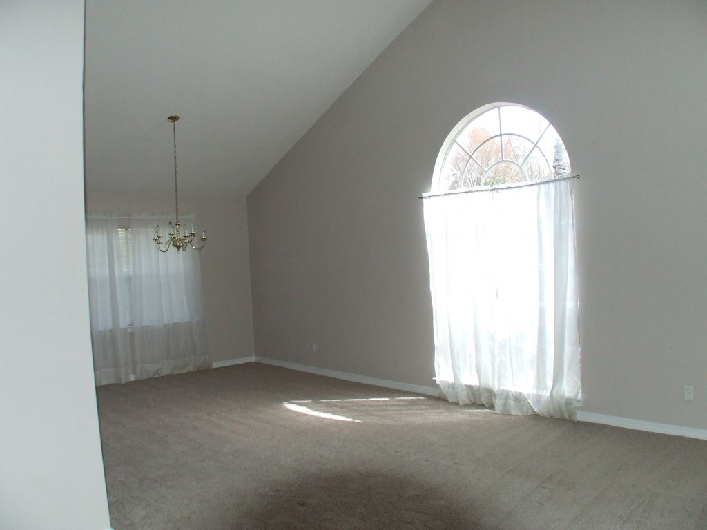 A room with a chandelier and a large window.