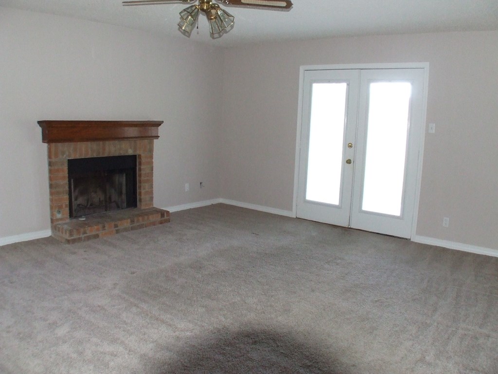 A room with a fireplace and a ceiling fan.