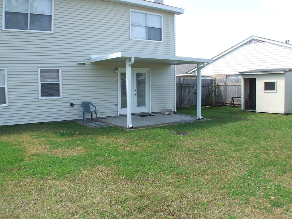 A house with a covered patio and a lawn.
