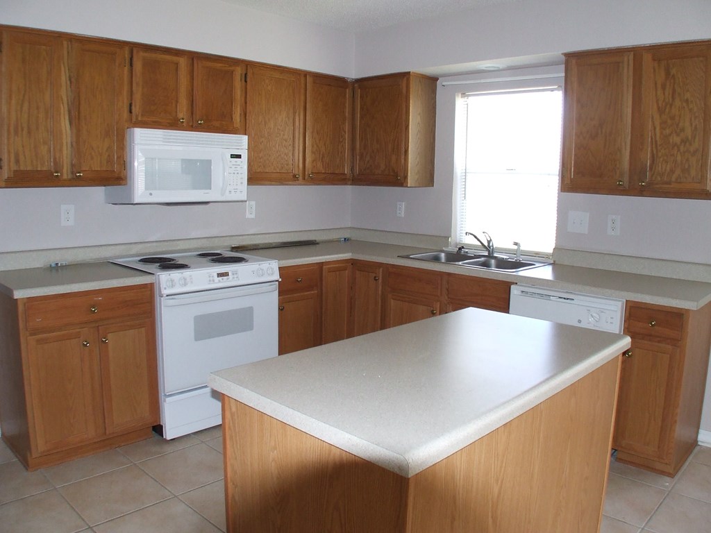 A kitchen with wooden cabinets and a white counter.