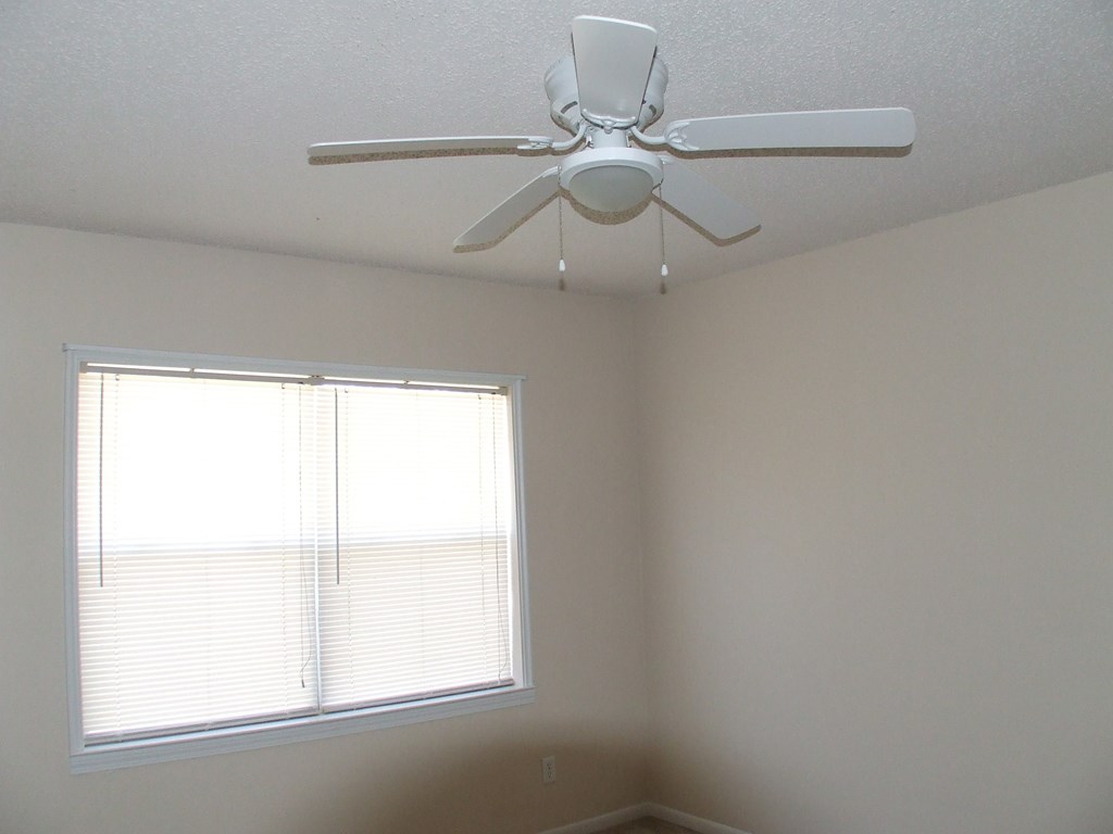 A white ceiling fan in a room with a window.