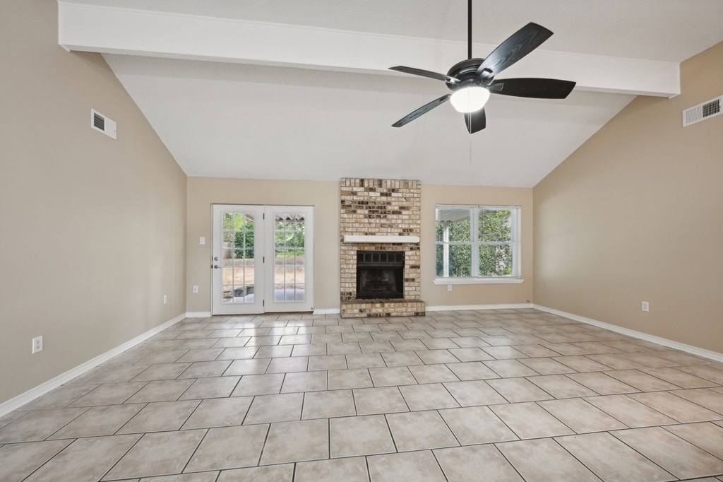 A spacious room with a fireplace and a ceiling fan.