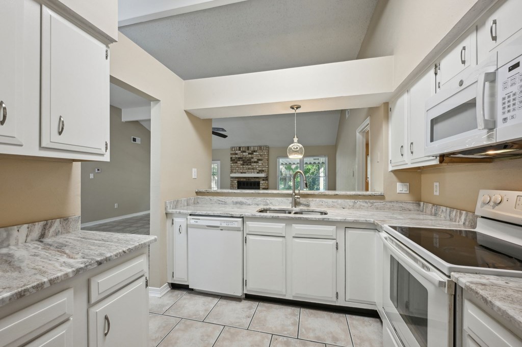 A kitchen with white cabinets and granite countertops.