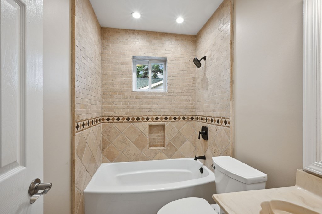 A bathroom with a tub, toilet, and sink.