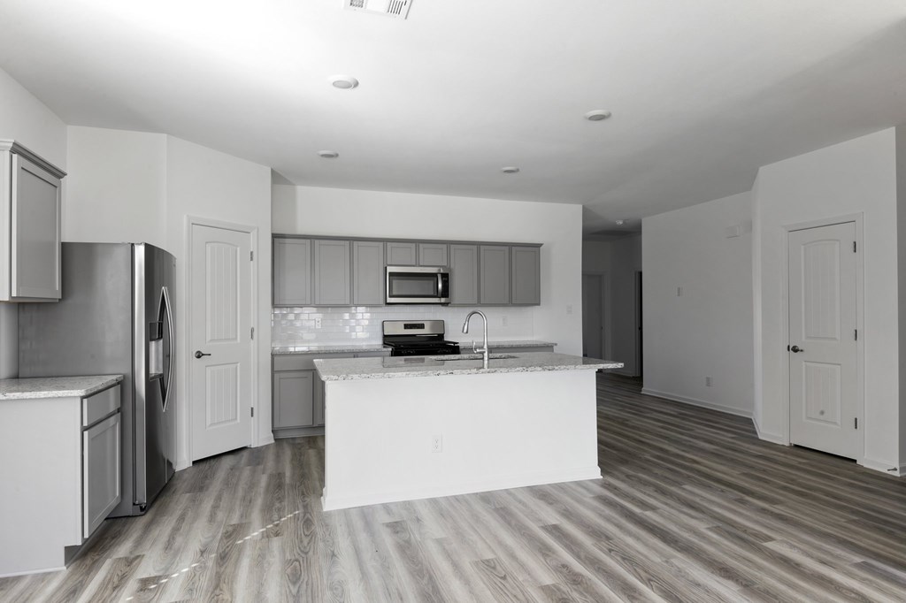 A kitchen with a white island and wooden floors.