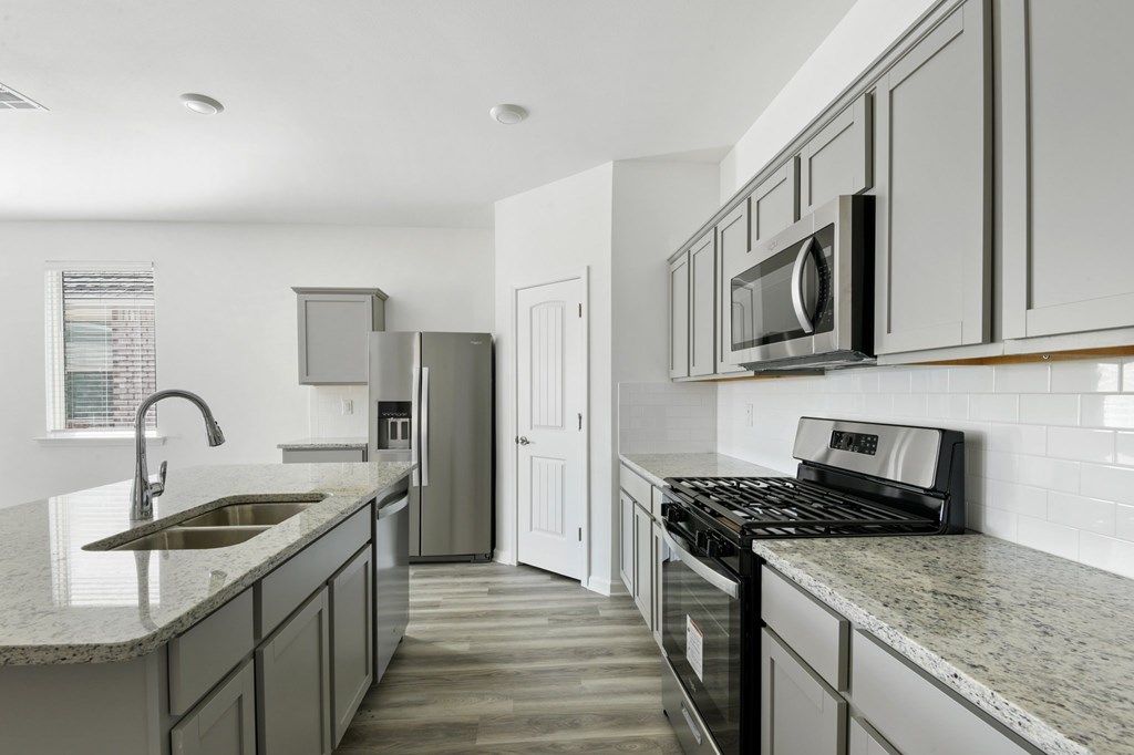 A kitchen with a sink, stove, and microwave.