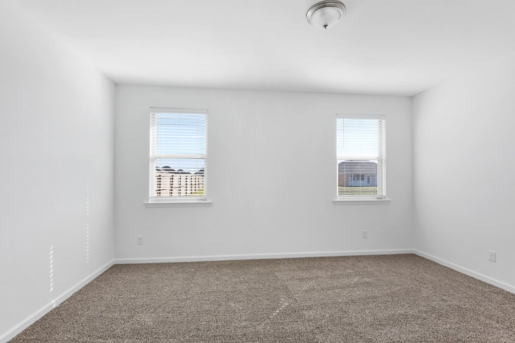 A room with two windows and carpeted floor.