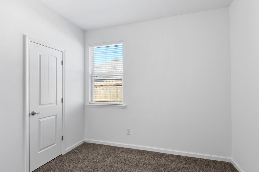 A white door is on the left side of a room with a window on the right.