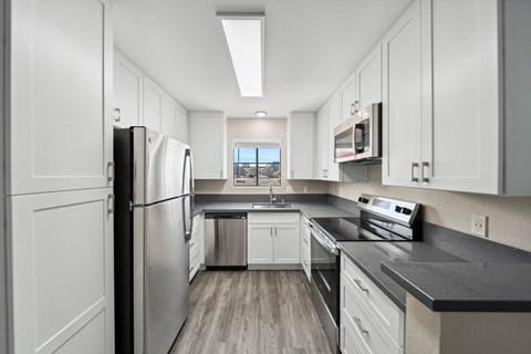 A modern kitchen with white cabinets and stainless steel appliances.