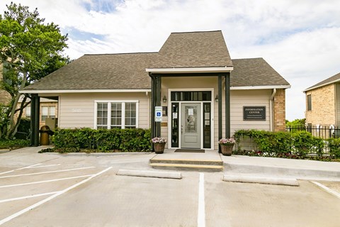 the front of a tan house with a parking lot and a door