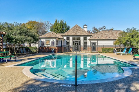 a swimming pool with chairs and a house in the background