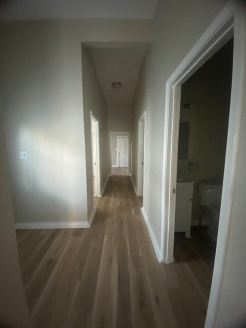 a hallway with wooden floors and white walls and a door