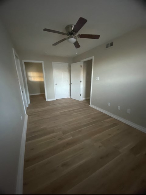 a empty room with wooden floors and a ceiling fan