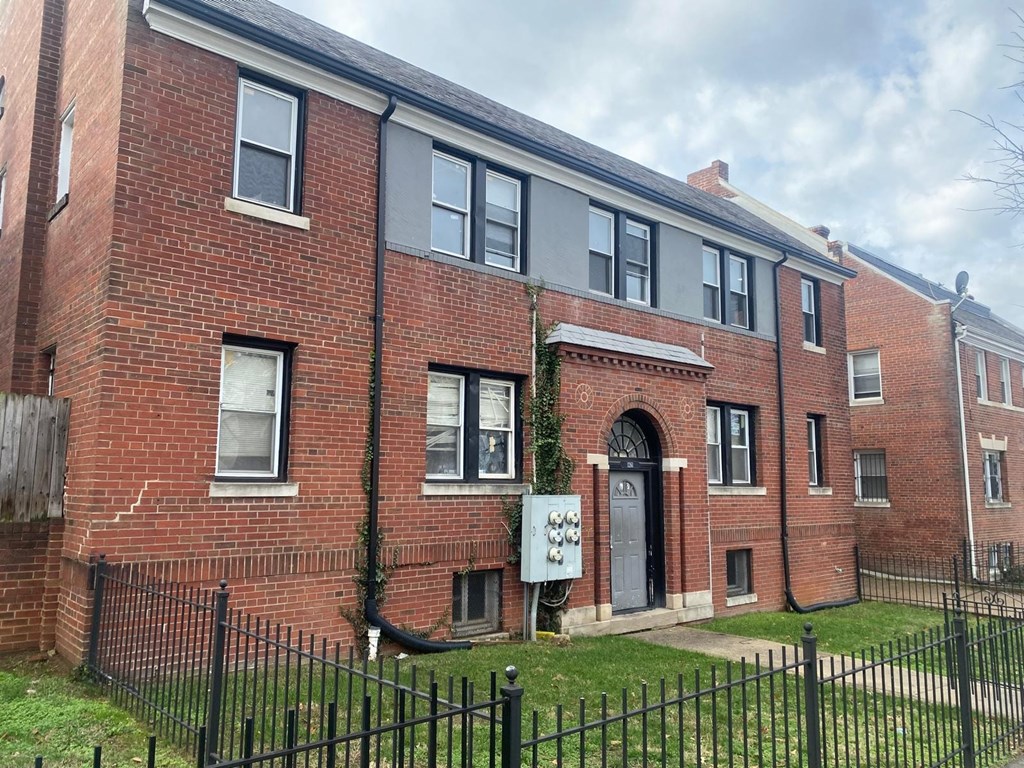 A red brick building with a black fence in front.