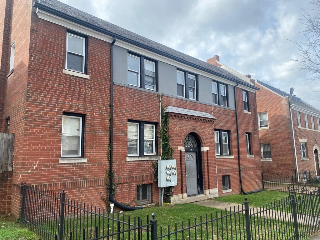 A red brick building with a black fence in front.