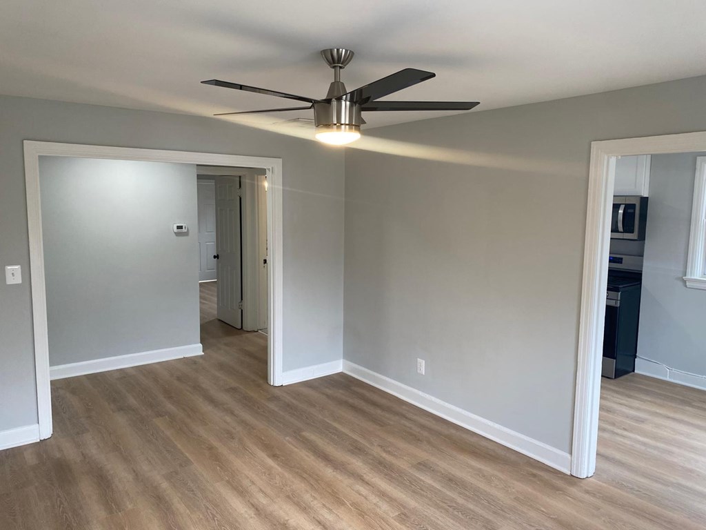 A room with a ceiling fan and light fixture, and a wood floor.