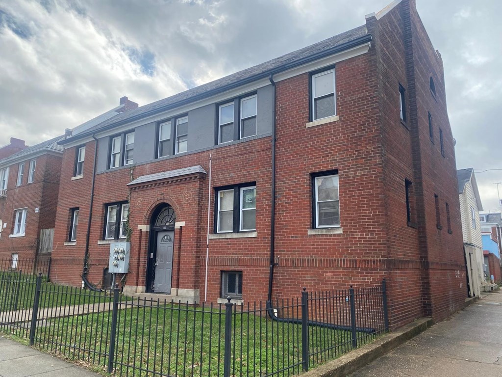 A red brick building with a black fence in front.