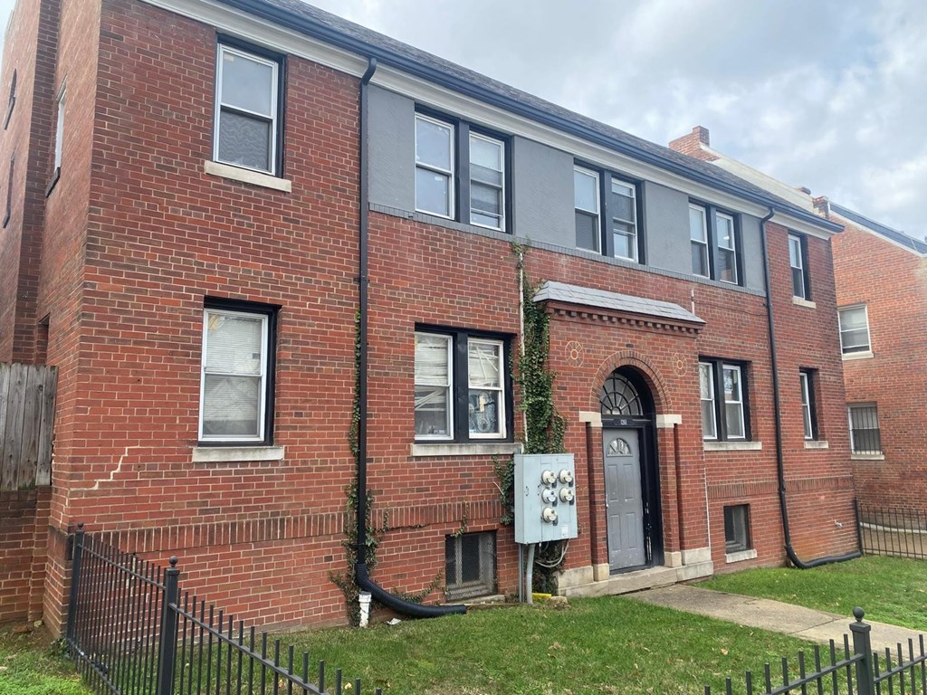 A red brick building with a black iron fence in front.