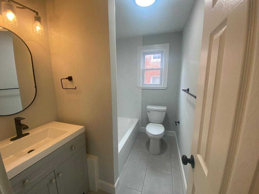A bathroom with a toilet, sink, and mirror.