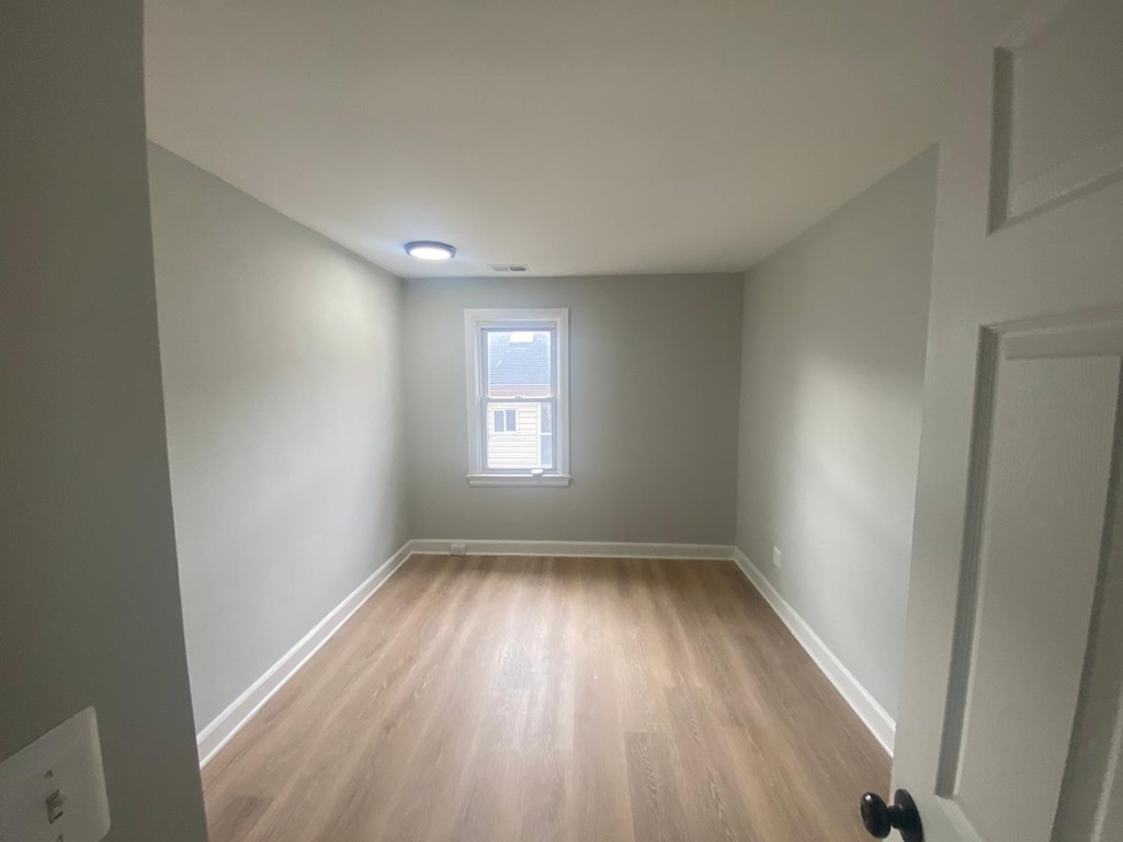 A room with a window and wooden flooring.
