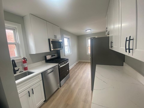 A kitchen with white cabinets and a black refrigerator.