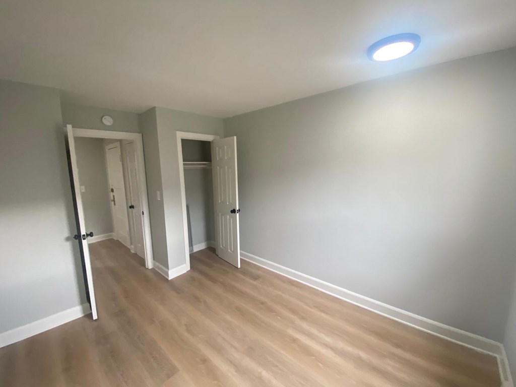 A room with a light on the ceiling and a doorway leading to another room.