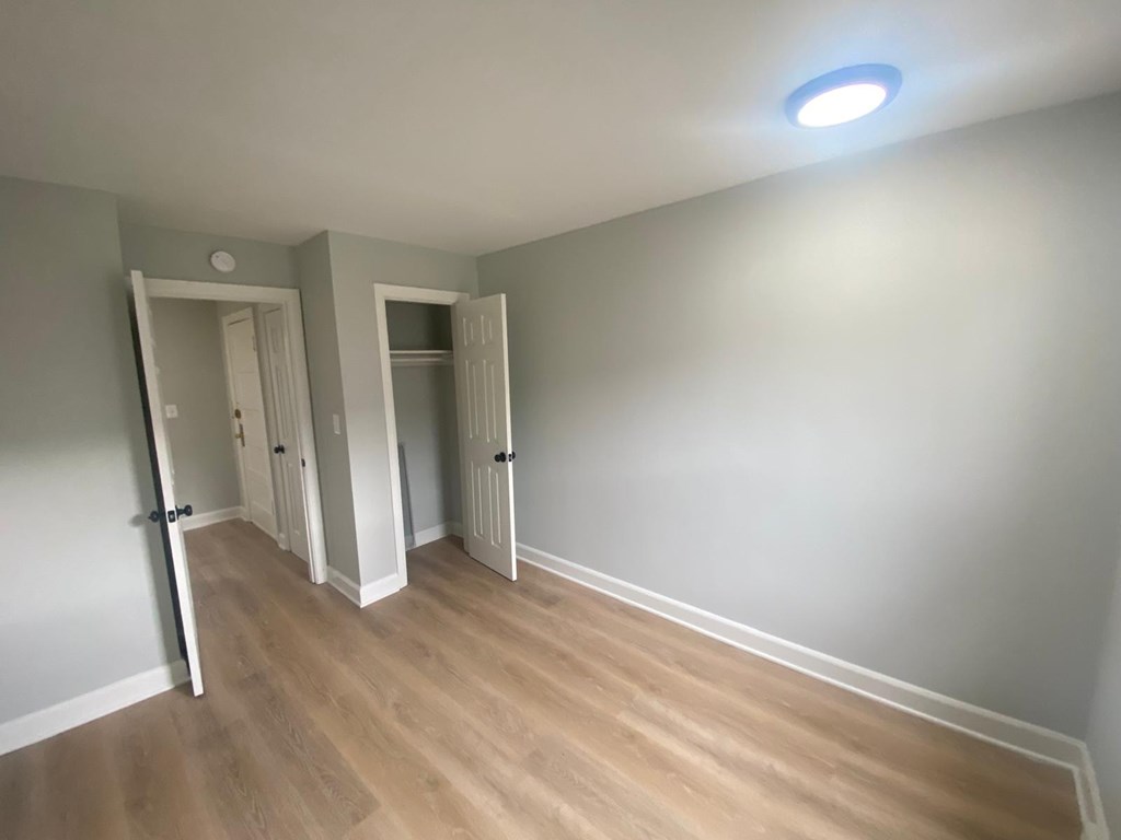 A room with wooden flooring and two open doors.