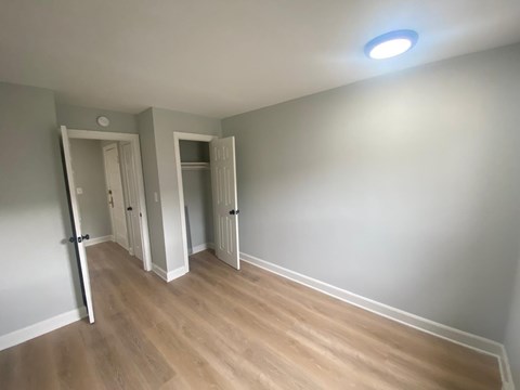 A room with wooden flooring and two open doors.