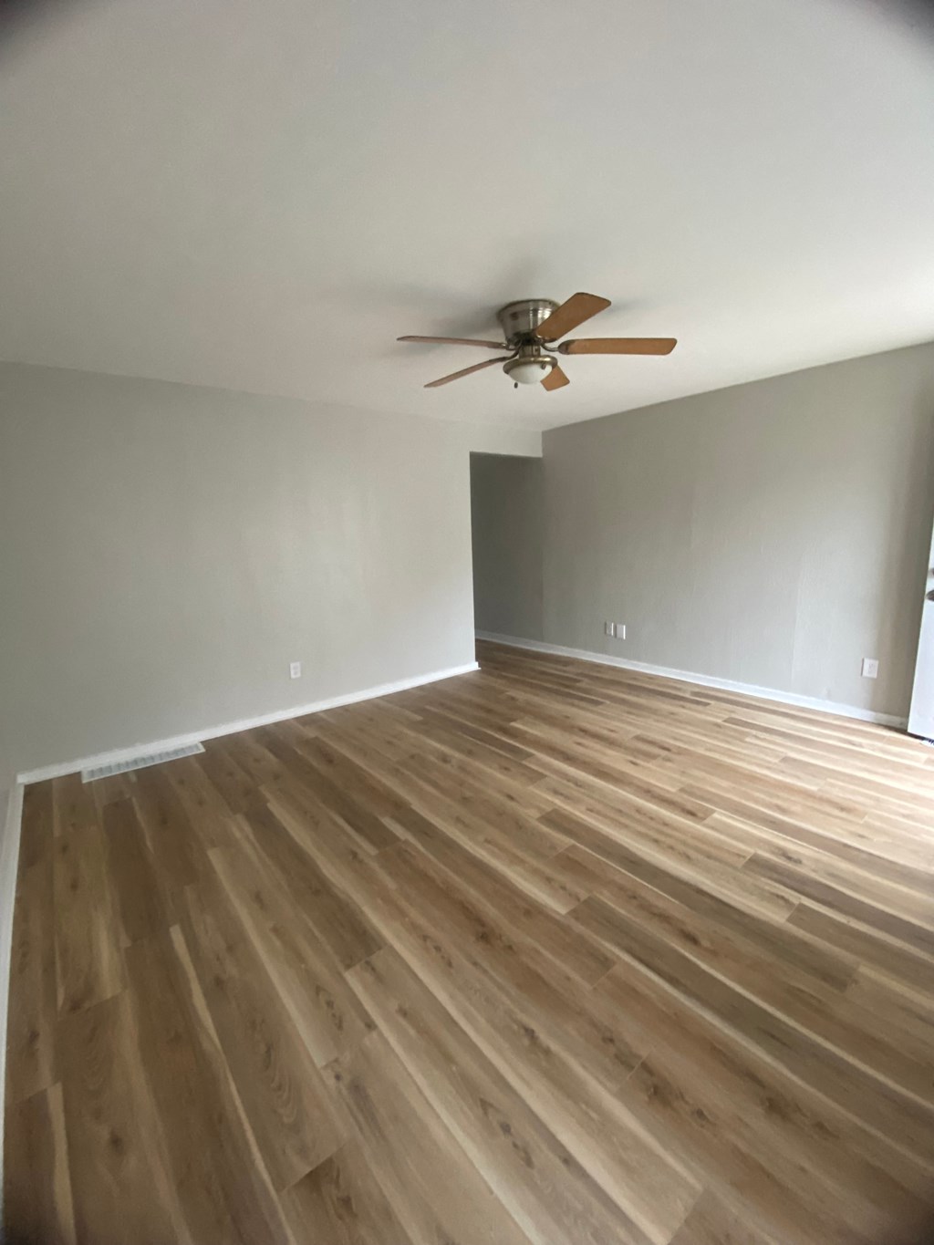 an empty living room with wooden floors and a ceiling fan